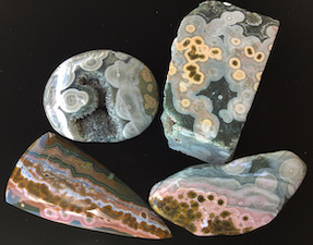 'Lost': Four different specimens (two palm stones, one small faced rough and a cab) that came from the same variety of Ocean Jasper. The cab was cut almost 18 years ago and is from a much more colorful area of this variety. The other specimens comparitively have 'muted colors' and were likely cut or polished much later, and perhaps mined later. It was reportedly common to mine and process the more colorful areas of Ocean Jasper first, with lesser color specimens left in-situ or warehoused. Faced rough length ~65mm.